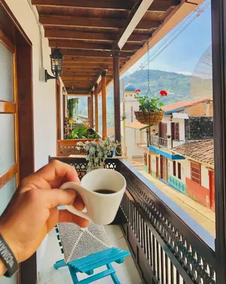a person holding a cup of coffee on a balcony at Hotel Plenitud Jardín in Jardin