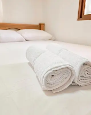 a stack of towels on a white bed at Hotel Villa Santa María in Santa Fe de Antioquia