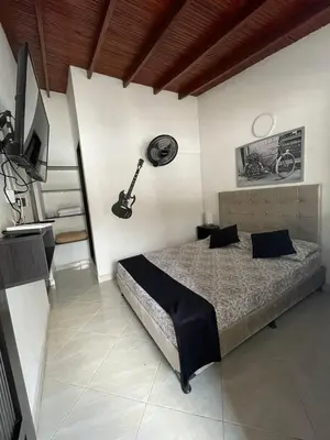 a bedroom with a bed and a guitar on the wall at Hotel San Pablo boutique H9 in Medellín