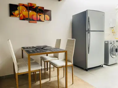 a dining room table with chairs and a refrigerator at Hermoso apartamento con estacionamiento in Medellín
