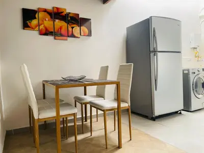 a dining room with a table and chairs and a refrigerator at Hermoso apartamento con estacionamiento in Medellín