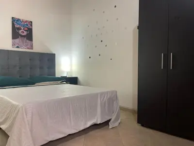 a bedroom with a white bed and a black cabinet at Hermoso apartamento con estacionamiento in Medellín
