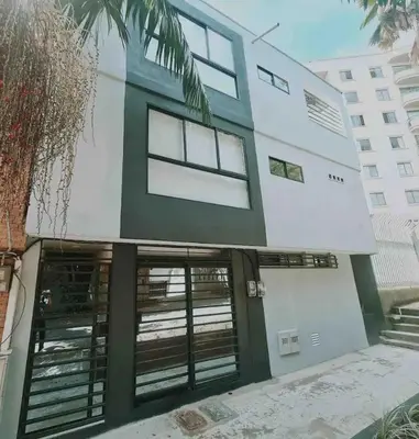 a white building with windows and a palm tree at Duplex apartment in Medellín