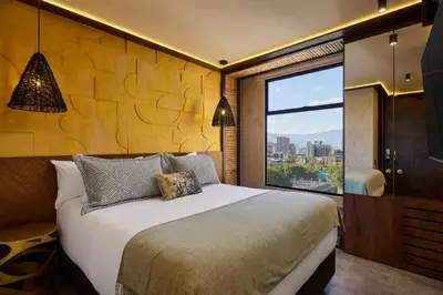 a bedroom with a large bed and a large window at Golden Valley Hotel in Medellín