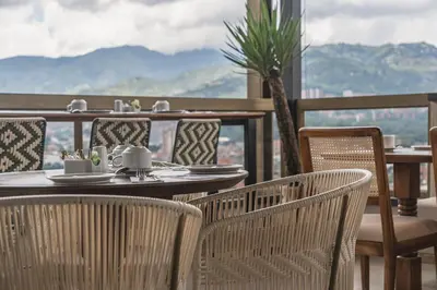 a table and chairs on a balcony with a view at Golden Valley Hotel in Medellín