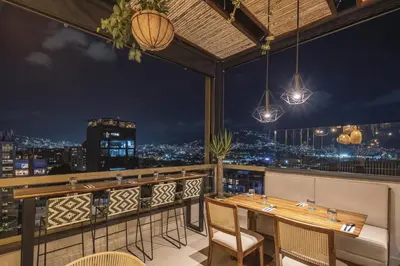 a restaurant with a view of the city at night at Golden Valley Hotel in Medellín
