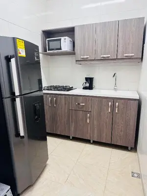 a kitchen with wooden cabinets and a black refrigerator at Apartamento en San Diego La Candelaria cerca al centro de Medellín in Medellín