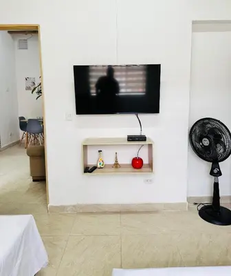 a flat screen tv on a white wall with two figurines at Apartamento en San Diego La Candelaria cerca al centro de Medellín in Medellín