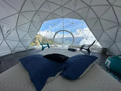 a bed in a yurt with a large window at Fabrica de Rios Glamping in Manizales