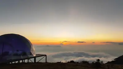 a tent on top of a mountain with a view of clouds at Fabrica de Rios Glamping in Manizales
