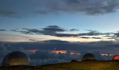 a group of domes on a field with a cloudy sky at Fabrica de Rios Glamping in Manizales