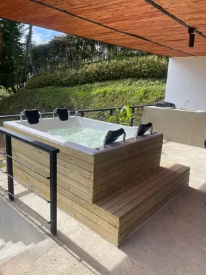 a hot tub sitting on a wooden bench under a umbrella at Serenity house Guatapé in Guatapé