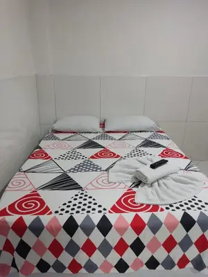 a bed with a patterned comforter and towels on it at TURISTAS Hostel in Jardin
