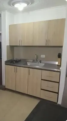 a kitchen with a sink and wooden cabinets at Acogedor Aparta Hotel para 3H Belén Rosales apt 202 in Medellín