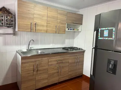 a kitchen with wooden cabinets and a stainless steel refrigerator at En la Zona Rosa, a una cuadra del Parque in Urrao