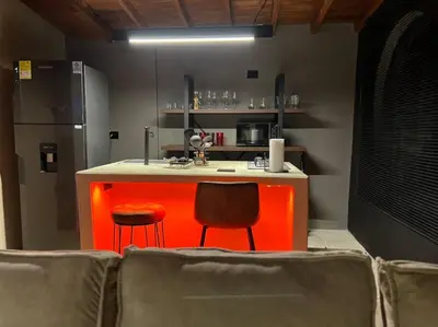 a kitchen with an orange counter and two chairs at URBAN COMFORT POBLADO SUIT's in Medellín
