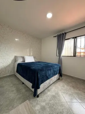 a bedroom with a bed with blue sheets and a window at Casa San Miguel 101 in Medellín