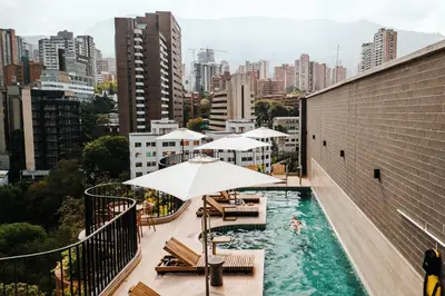 a rooftop pool with chairs and umbrellas on a building at Heiss Hotel By Jalo in Medellín