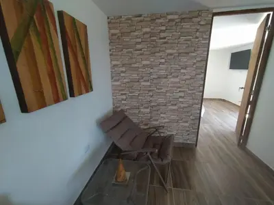 a living room with a chair and a brick wall at Cabaña Estancia Primavera in Guatapé