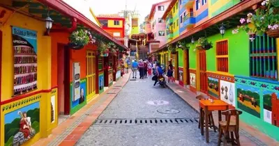 a street with colorful buildings and people walking down the street at Cabaña Estancia Primavera in Guatapé