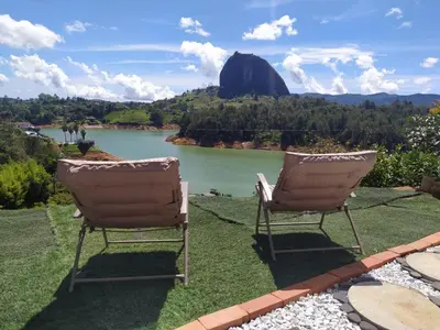 two chairs sitting on the grass near a lake at Cabaña Estancia Primavera in Guatapé