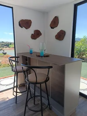 a bar with two stools and two glasses on the wall at Cabaña Estancia Primavera in Guatapé
