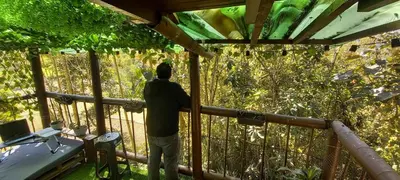 a man standing on a balcony looking at the forest at Boresta House -Santa Elena con vista al Bosque y terraza privada in Medellín
