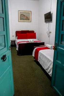 a room with two beds and a tv and a door at Hotel El Tesoro Sonson in Sonsón