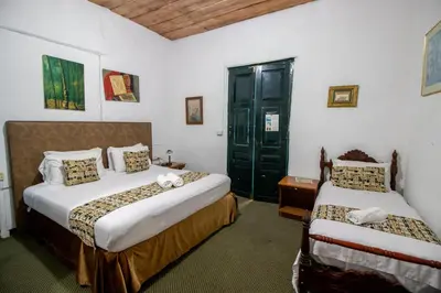 a bedroom with two beds and a green door at Hotel El Tesoro Sonson in Sonsón