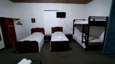 a room with three bunk beds and a television at Hotel El Tesoro Sonson in Sonsón