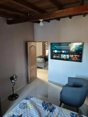 a room with a blue chair and a tv on the wall at EXCLUSIVO y ELEGANTE APARTAMENTO in Medellín
