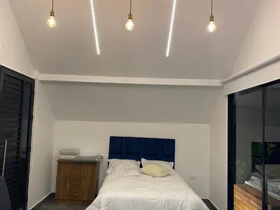 a bedroom with a bed with a blue headboard and lights at Finca hotel xamai in Guatapé