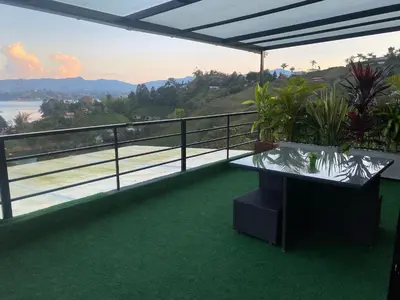 a balcony with a table and a view of the water at Finca hotel xamai in Guatapé