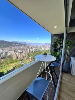 a balcony with a white table and two blue chairs at Amazing view Modern Apartment in Sabaneta in Sabaneta