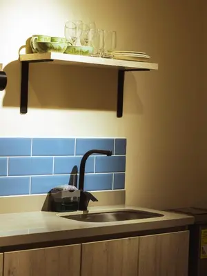a kitchen counter with a sink and glasses on a shelf at Casa Origo Hospedaje in Medellín