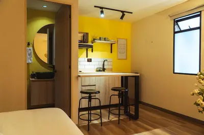 a small kitchen with two bar stools in a room at Casa Origo Hospedaje in Medellín
