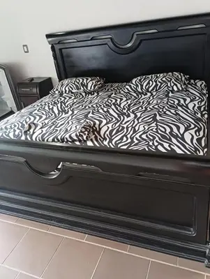 a bed with a black frame with a zebra print sheets at Agua Azul Cabaña 87 in San Jerónimo