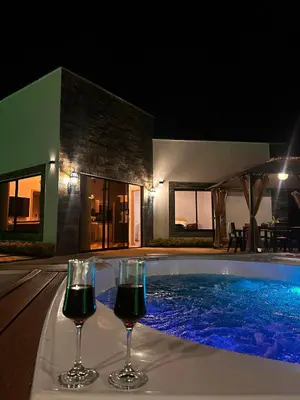two glasses of wine sitting next to a swimming pool at night at Casa Campestre Guatapé acceso directo a la represa in Guatapé