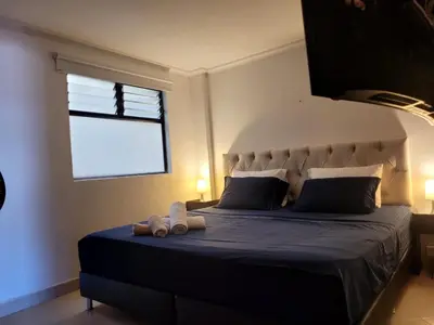 a bedroom with a large bed with blue sheets and a window at Alojamiento turístico laureles, buena ubicación in Medellín
