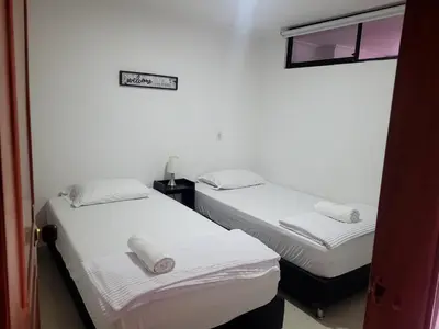 two beds in a room with white walls at Alojamiento turístico laureles, buena ubicación in Medellín