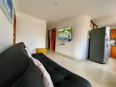 a living room with a couch and a tv at Alojamiento turístico laureles, buena ubicación in Medellín