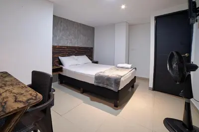 a bedroom with a bed and a desk and a television at Farum Hotels in Medellín