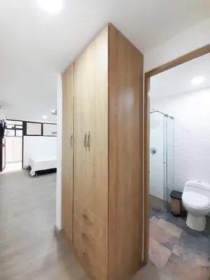 a bathroom with a toilet and a wooden cabinet at MEDELLIN CÓMODOS APARTAESTUDIOS in Medellín