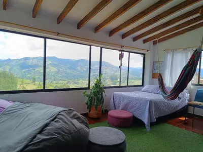 a bedroom with a bed and a hammock in front of a window at Apartamento Wiphala, Vista Panorámica in Jericó