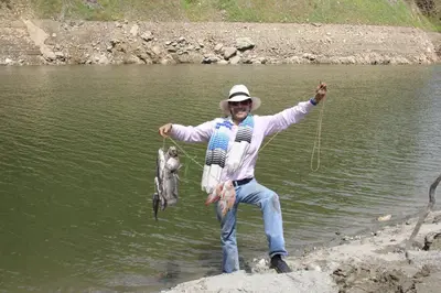 a man holding up a bunch of fish in the water at Ecohotel Campo Alegre Norcasia Caldas in Norcasia