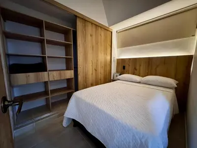 a bedroom with a white bed and wooden walls at Apartamentos de lujos para descansar Oasis in San Jerónimo