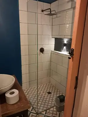 a shower with a glass door in a bathroom at Hostal Casa Primavera in Medellín