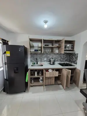 a kitchen with a black refrigerator and wooden cabinets at ECXEPCIONAL y ELEGANTE APARTAMENTO in Medellín
