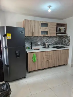 a kitchen with a black refrigerator and wooden cabinets at ECXEPCIONAL y ELEGANTE APARTAMENTO in Medellín