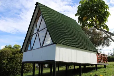 a small building with a green roof on a field at Pietrasanta Home in Rionegro